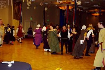 An open floor with people dancing, dressed in medieval garb.